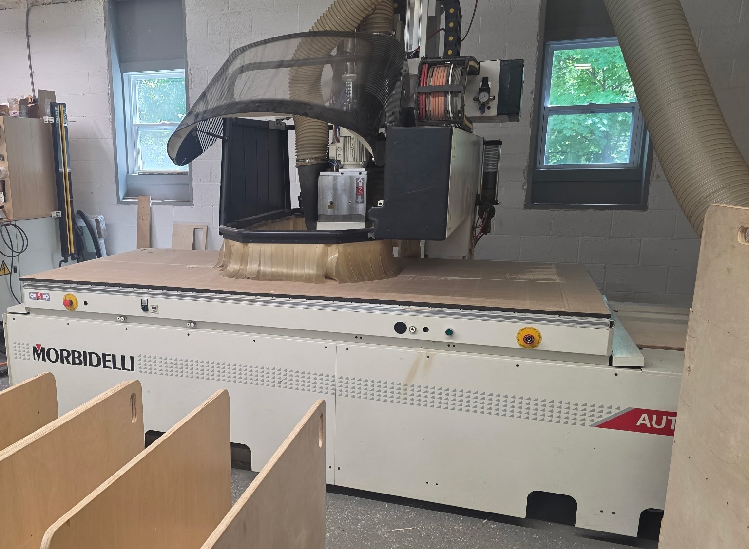 Morbidelli CNC router with the head raised over a sheet of plywood in the Riverwood Custom shop