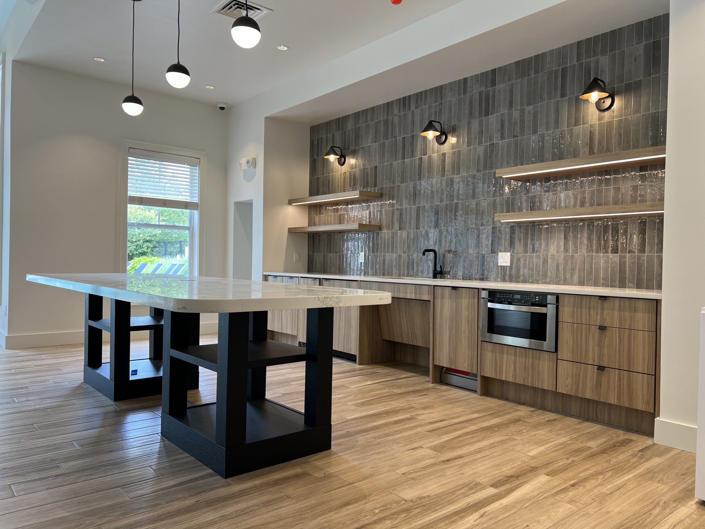 Office kitchenette with a waterfall-edge island and tile accent wall