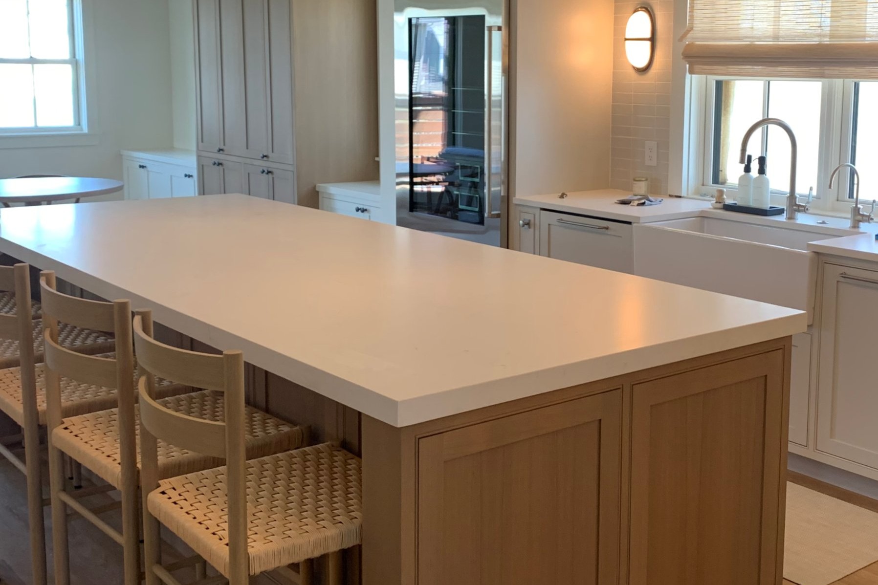 Light oak kitchen island with woven barstools and pendant lighting